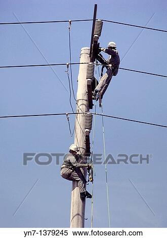 close view of two linesmen at work up their pole set against a clear blue sky View Large Photo Image Stock Photography - close view of two linesmen at work up their pole set against a clear blue sky. Fotosearch
