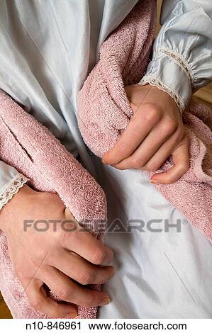Stock Image - Close_up of a young woman, wearing a nightgown, holding a towel.. Fotosearch