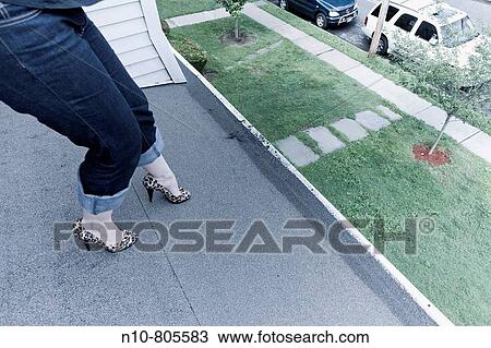 Stock Image - Close_up of a young woman wearing high heel shoes on the roof of her house.. Fotosearch