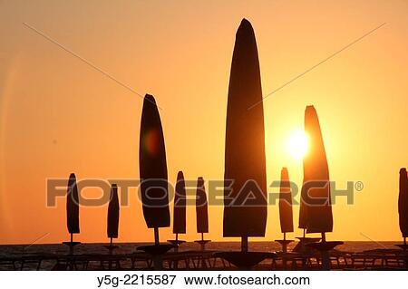 Stock Photo - closed umbrellas on beach by the tyrrenhian sea in italy. Fotosearch