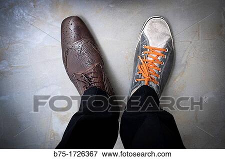 Stock Photo - closeup of a man feet with different shoes. Fotosearch
