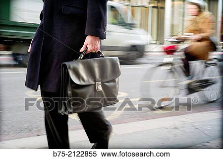 Closeup of an unrecognizable executive with portfolio walking down the street with traffic in London, England, UK, Europe. View Large Photo Image Stock Photography - Closeup of an unrecognizable executive with portfolio walking down the street with traffic in London, England, UK, Europe.. Fotosearch