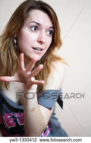 Stock Image - closeup of face of pretty girl against light wall grimasing. Fotosearch