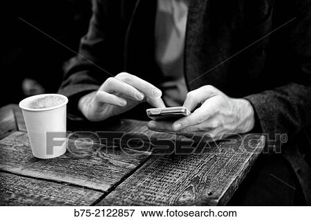 Closeup of hands of a man having coffee and manipulating a cell phone in a coffee shop in London, England, UK, Europe View Large Photo Image Stock Photo - Closeup of hands of a man having coffee and manipulating a cell phone in a coffee shop in London, England, UK, Europe. Fotosearch