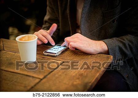 Closeup of hands of a man having coffee and manipulating a cell phone in a coffee shop in London, England, UK, Europe View Large Photo Image Stock Photograph - Closeup of hands of a man having coffee and manipulating a cell phone in a coffee shop in London, England, UK, Europe. Fotosearch
