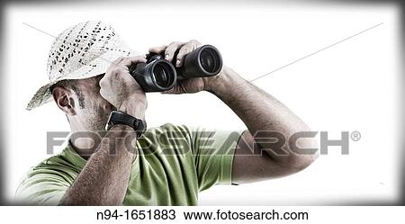 Stock Image - Closeup of man with hat looking through binoculars.. Fotosearch