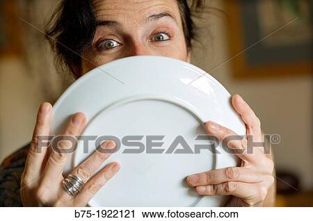 Stock Image - Closeup of woman with expression of surprise with a plate in her hands. Fotosearch