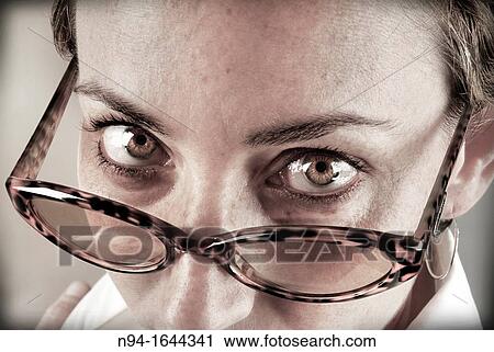 Closeup of young woman staring at the camera above his glasses. View Large Photo Image Stock Image - Closeup of young woman staring at the camera above his glasses.. Fotosearch