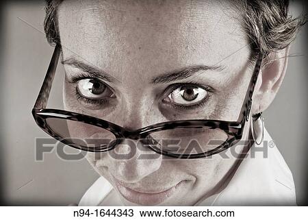 Closeup of young woman staring at the camera above his glasses. View Large Photo Image Stock Image - Closeup of young woman staring at the camera above his glasses.. Fotosearch