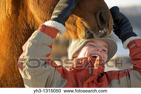 Closeup portrait of a young Caucasian boy playing with his companion horse in the winter time View Large Photo Image Stock Image - Closeup portrait of a young Caucasian boy playing with his companion horse in the winter time. Fotosearch