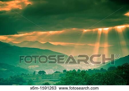 Stock Image - Clouds and sunbeams Baztan valley, Navarre, Spain. Fotosearch