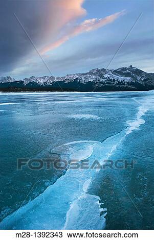 Stock Image - Clouds glowing in a winter sunset over the wind polished ice of Abraham Lake, Alberta Canada. Fotosearch