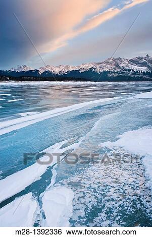 Stock Photograph - Clouds glowing in a winter sunset over the wind polished ice of Abraham Lake, Alberta Canada. Fotosearch