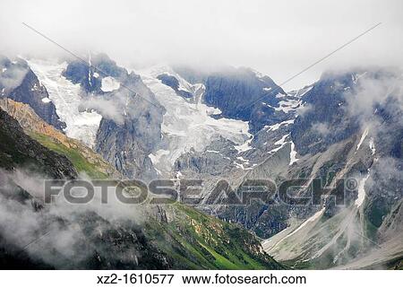 Stock Photo - Clouds over snowy mountain in Tibet. Fotosearch