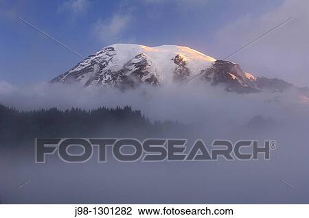 Stock Image - Clouds surrounding summit of Mount Rainier at sunrise Cascade Range, Pierce County, Mount Rainier National Park, Washington State, USA, America. Fotosearch