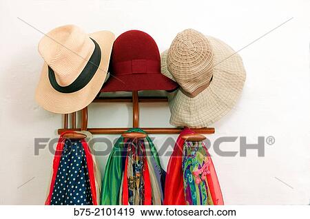 Stock Photo - Coat rack with three hats and scarves of various colors. Fotosearch