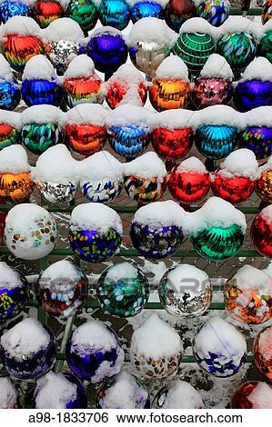 Stock Photograph - collection of colored glass balls decoration in garden in winter with snow. Fotosearch