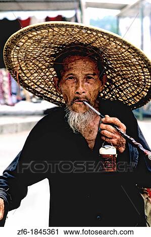 Stock Image - Colorful portrait of old Chinese man smoking a pipe in Yangshou China.. Fotosearch