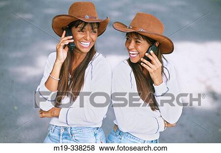 Stock Photo - Columbian identical twins on cell phone. Fotosearch