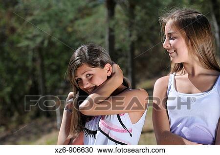 Stock Image - combing girl in the park while talking to a friend. Fotosearch