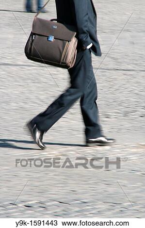 Commuter walking with bag in street in town View Large Photo Image Stock Image - Commuter walking with bag in street in town. Fotosearch