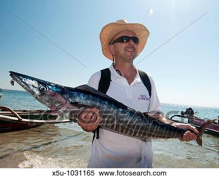 Stock Photography - Competitors in timor-Leste's first sport fishing competition, many were international and had travelled from Darwin, NT Australia this man has caught a wahoo. Fotosearch