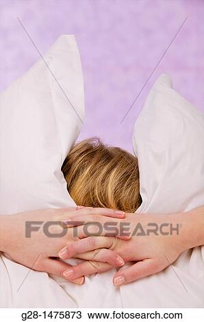 Concept: young woman burrying herself in her pillows because of overstress or fear, depression, or desire to cut herself from the world around View Large Photo Image Stock Image - Concept: young woman burrying herself in her pillows because of overstress or fear, depression, or desire to cut herself from the world around. Fotosearch