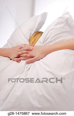 Concept: young woman burrying herself in her pillows because of overstress or fear, depression, or desire to cut herself from the world around View Large Photo Image Stock Photo - Concept: young woman burrying herself in her pillows because of overstress or fear, depression, or desire to cut herself from the world around. Fotosearch