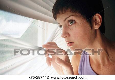 Stock Image - concerned woman looking out window. Fotosearch