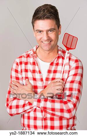 Picture - Confident adult male hold flyswatter and smile. Fotosearch