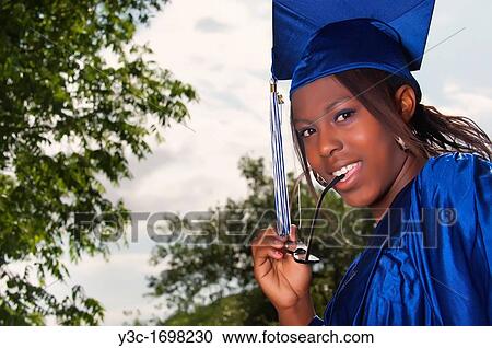 Stock Image - Confident african american female student dressed for graduation in cap and gown. Fotosearch
