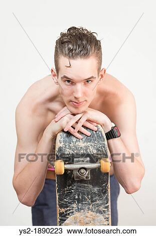 Confident and cool young adult man holding a skateboard and looking at camera View Large Photo Image Stock Image - Confident and cool young adult man holding a skateboard and looking at camera. Fotosearch