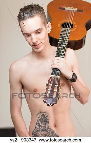 Stock Photo - Confident and cool young adult man with tattoo holding a guitar. Fotosearch