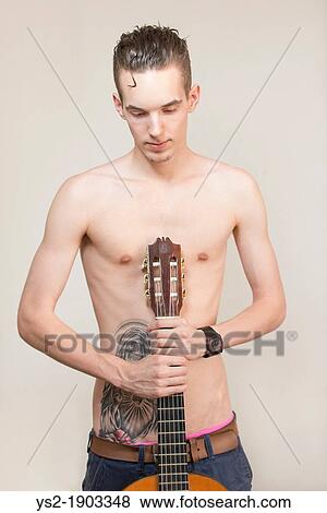 Confident and cool young adult man with tattoo holding a guitar View Large Photo Image Stock Photo - Confident and cool young adult man with tattoo holding a guitar. Fotosearch