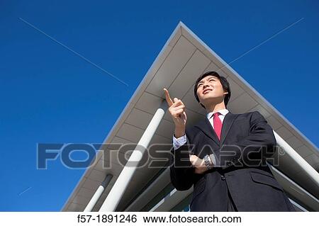 Confident young Asian businessman standing outside his office building View Large Photo Image Stock Photograph - Confident young Asian businessman standing outside his office building. Fotosearch