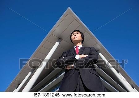 Confident young Asian businessman standing outside his office building View Large Photo Image Stock Photography - Confident young Asian businessman standing outside his office building. Fotosearch