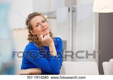 Confident young businesswoman sitting at a table View Large Photo Image Stock Image - Confident young businesswoman sitting at a table. Fotosearch