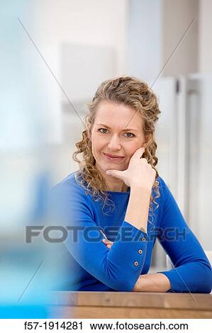Confident young businesswoman sitting at a table View Large Photo Image Stock Image - Confident young businesswoman sitting at a table. Fotosearch