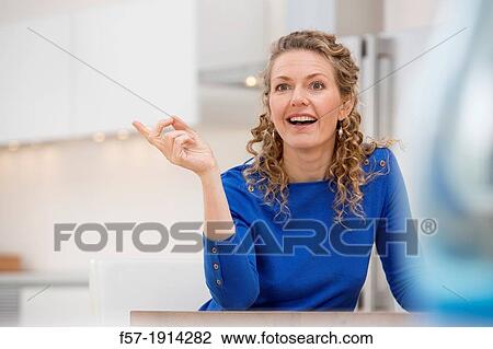 Stock Image - Confident young businesswoman sitting at a table. Fotosearch