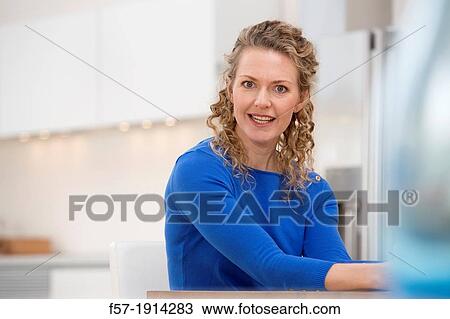 Confident young businesswoman sitting at a table View Large Photo Image Stock Image - Confident young businesswoman sitting at a table. Fotosearch