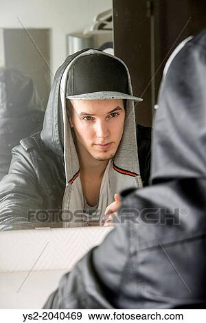 Confident young man with cool attitude sitting in front of mirror. View Large Photo Image Stock Photo - Confident young man with cool attitude sitting in front of mirror.. Fotosearch
