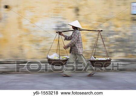Conical hat woman with banana baskets walks from market Hoi An historic town mid Vietnam View Large Photo Image Stock Photo - Conical hat woman with banana baskets walks from market Hoi An historic town mid Vietnam. Fotosearch