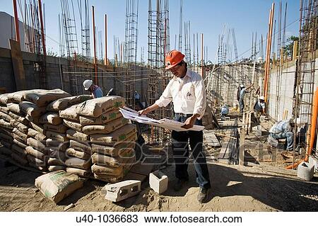 Stock Image - Construction site, architect with blueprints. Fotosearch