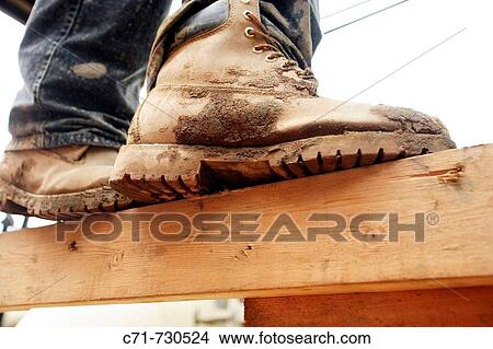 Construction worker muddy boots standing on wood plank from below View Large Photo Image Picture - Construction worker muddy boots standing on wood plank from below. Fotosearch