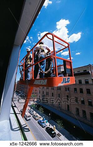 Construction workers in cherry picker outside high rise building, Denver, CO, USA View Large Photo Image Stock Photograph - Construction workers in cherry picker outside high rise building, Denver, CO, USA. Fotosearch
