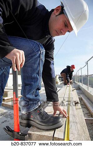 Construction workers measuring, personal protective equipment, housing construction View Large Photo Image Stock Photo - Construction workers measuring, personal protective equipment, housing construction. Fotosearch