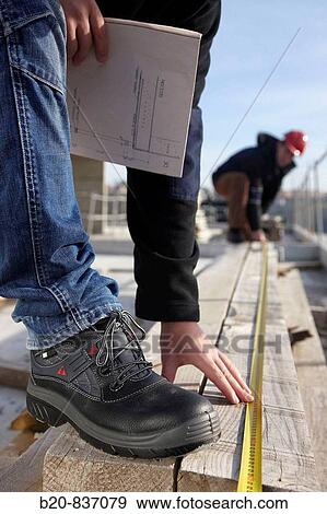 Construction workers measuring, personal protective equipment, housing construction View Large Photo Image Stock Photo - Construction workers measuring, personal protective equipment, housing construction. Fotosearch