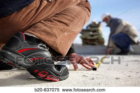 Stock Photography - Construction workers measuring, personal protective equipment, housing construction. Fotosearch