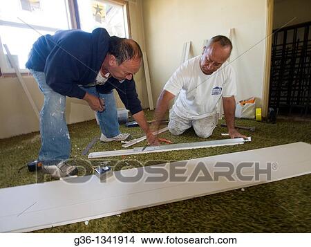 Picture - Construction workers repair a foreclosed home that was vandalized in Los Angeles, California, United States Black Shirt: Marco Moreno / White Pants: Antonio Perez / Blue Jeans: Fernando Perez. Fotosearch