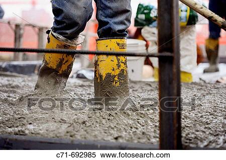 Stock Photography - Construction/Mason worker with yellow boots deep in concrete/cement. Fotosearch